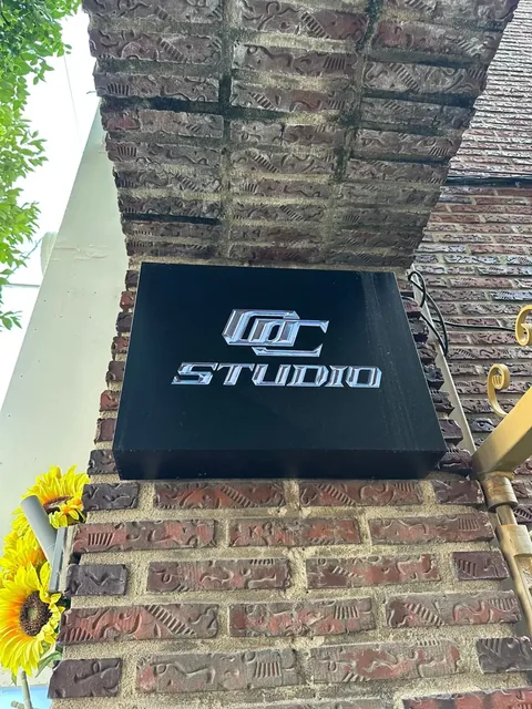 Black OC STUDIO sign on a brick pillar