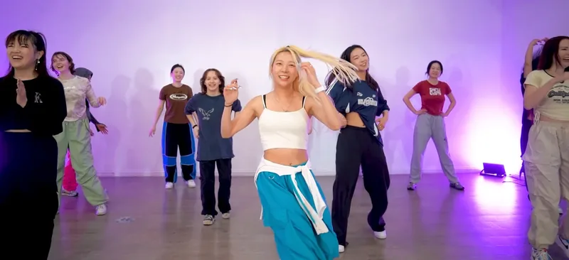 Ana dancing with smiling students in a bright studio